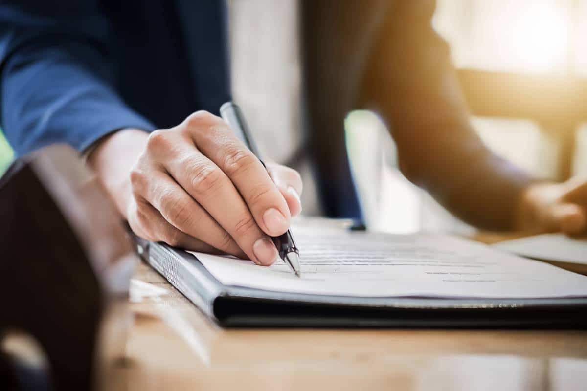 Un homme d'affaires signant un document pour emprunter une petite somme avec un stylo.
