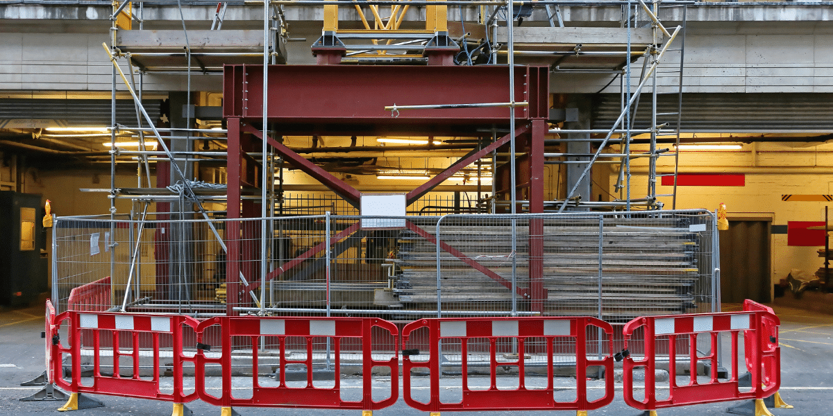 Échafaudage de construction dans une barrière sécurisée sur un chantier intérieur.|Barrière de chantier|Clôture de chantier
